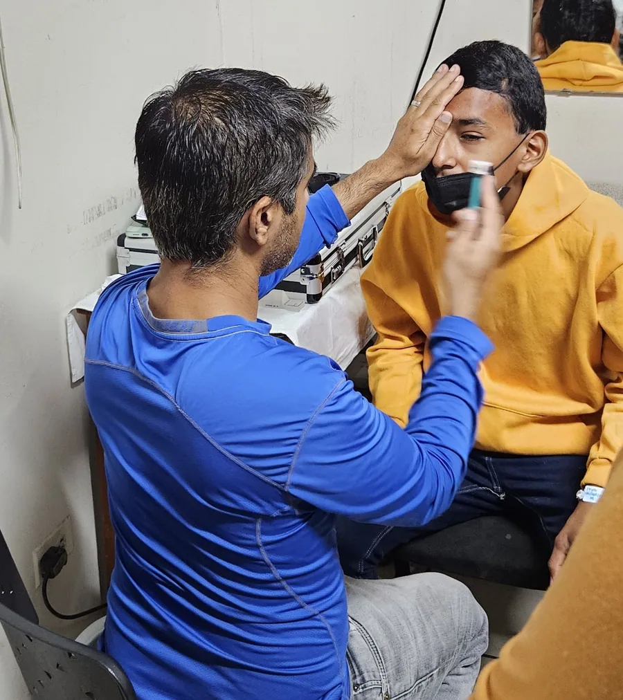 A clinician checks an adult patient's eye after treatment.