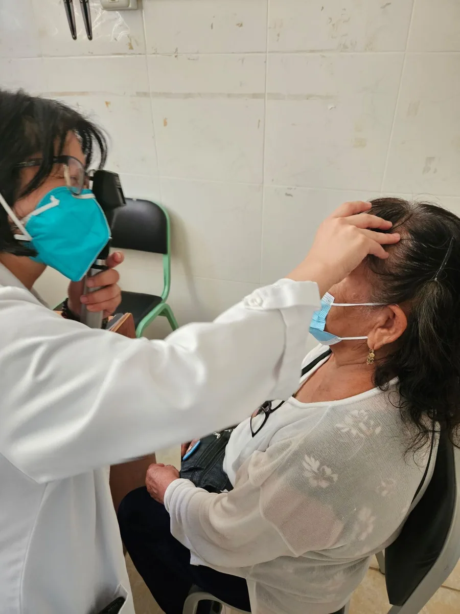 An optometrist examines an adult patient's eye.